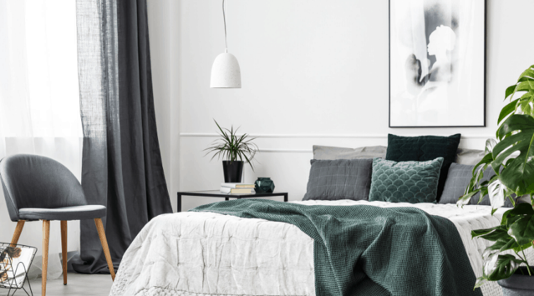 Decorated bedroom, white bedding with pillows and a green throw over the bed.