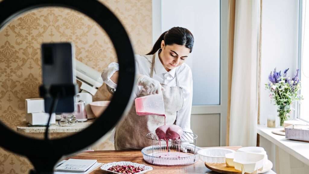 woman filming herself baking with the phone on a ring light kit. 