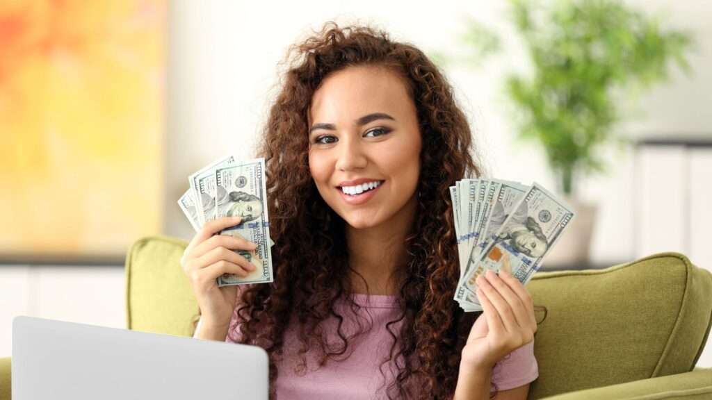 Close up shot of a woman holding money in both hands. 25 Ways to Earn Real Money From Home