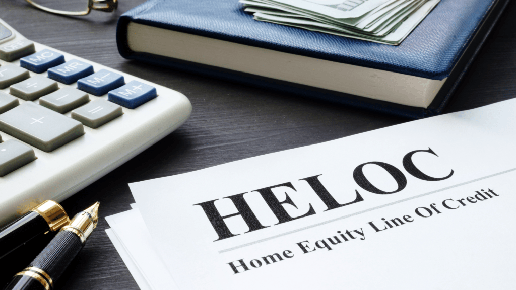 Books on a table with a sheet of paper that has written on it HELOC - Home Equity Line of Credit. 