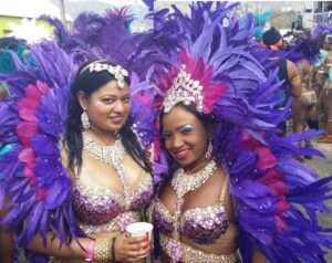 Two women in jeweled and purple feathered carnival costumes in in Trinidad. 